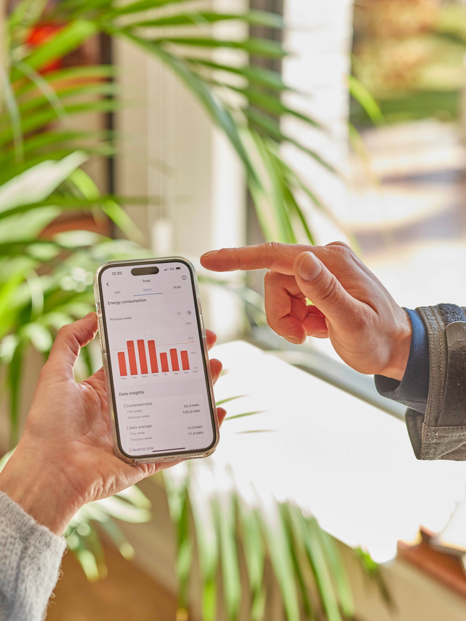 Two people reviewing heat pump performance data on a smartphone app together