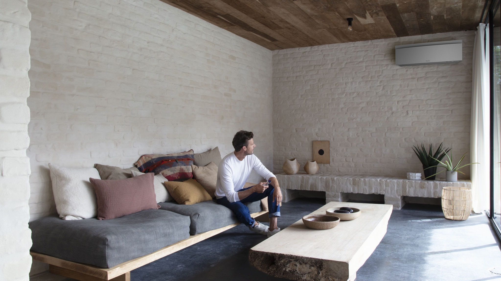 Man controlling his air conditioner in the living room with a remote