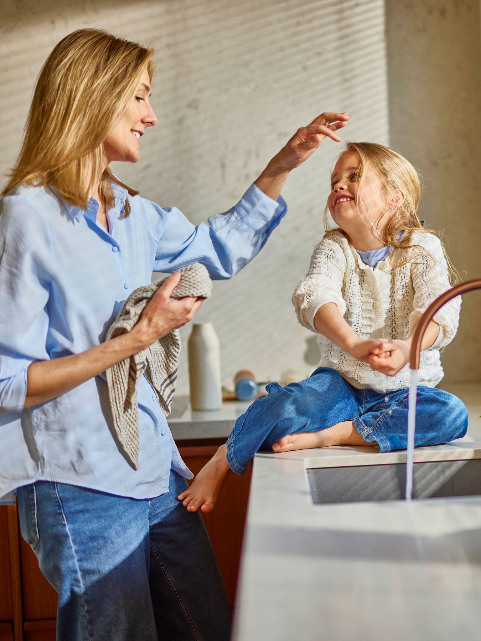 Mother washing child’s face with warm water in energy-efficient bathroom