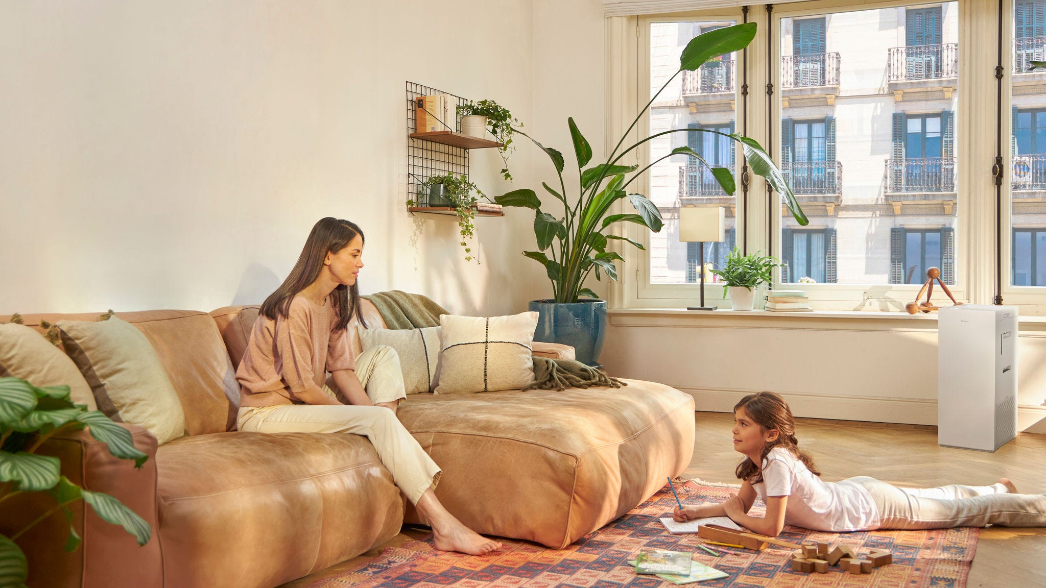 Mother and child at home with air purifier reducing indoor allergens and improving air quality