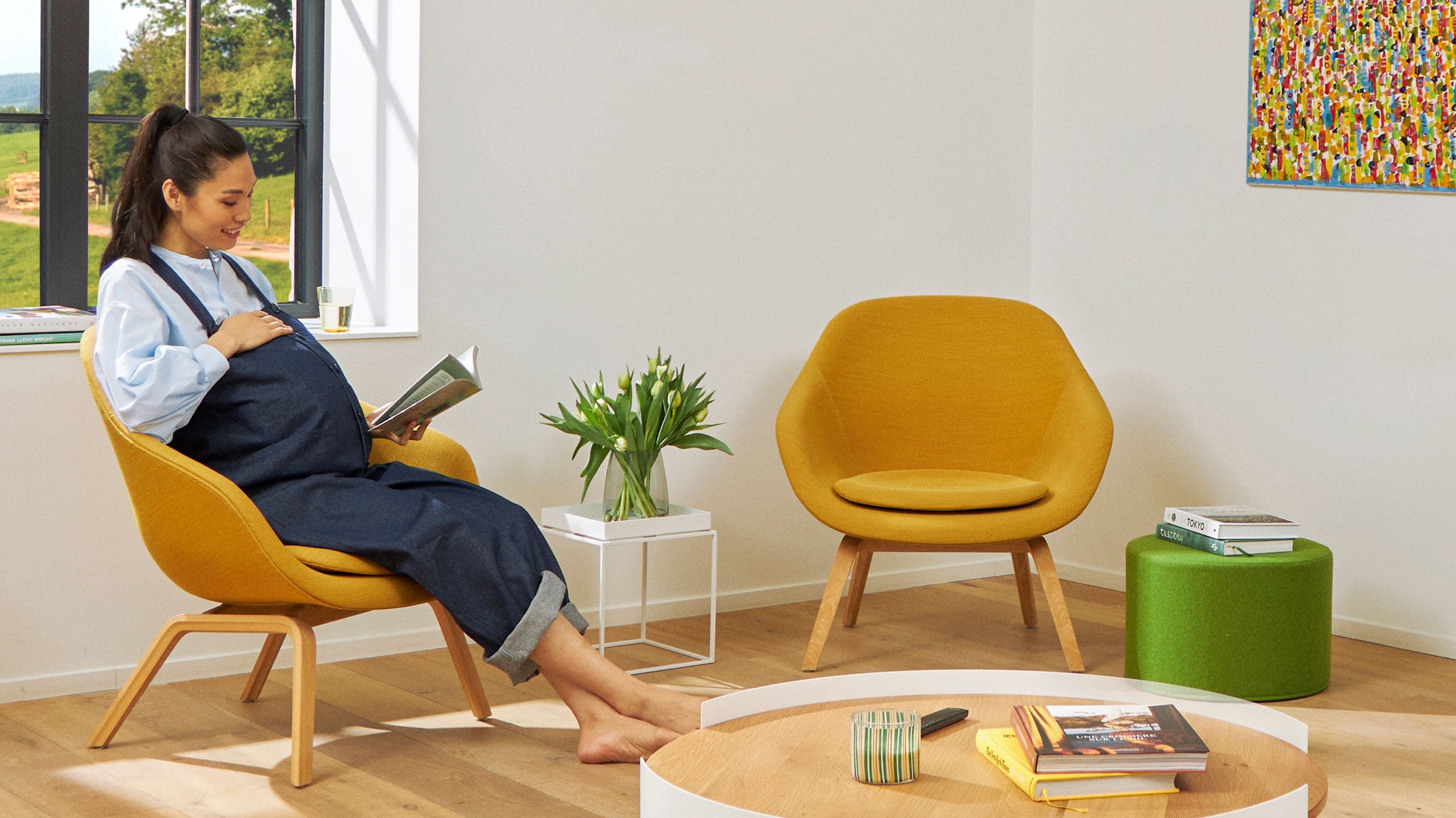 Pregnant woman reading a book in her chair enjoying clean air in her living room