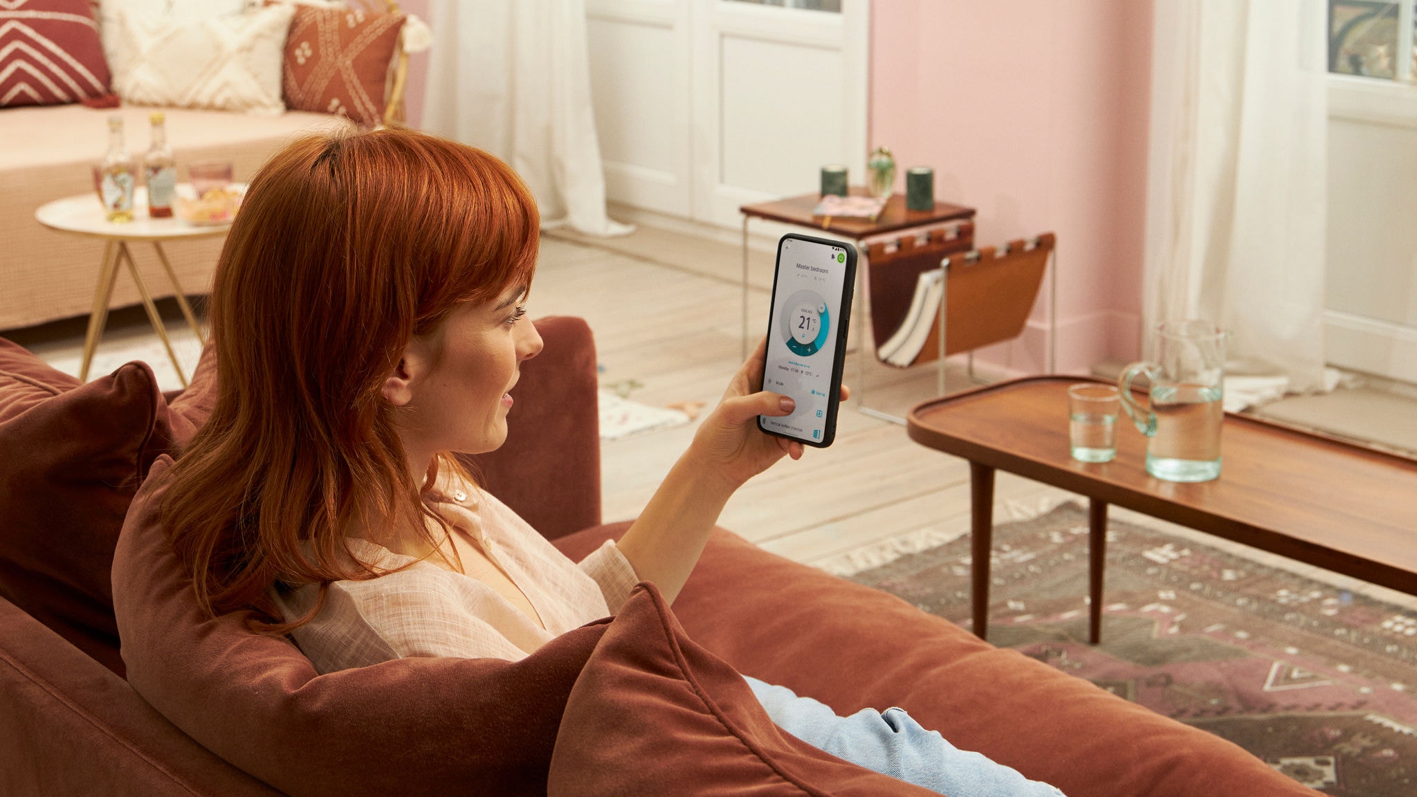 Woman sitting on a sofa at home using the Onecta app on her mobile phone