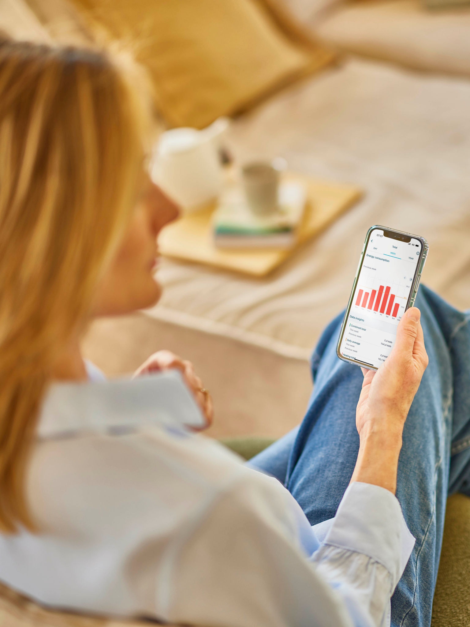 A woman with blonde hair looking at her energy consumption on an app on her phone