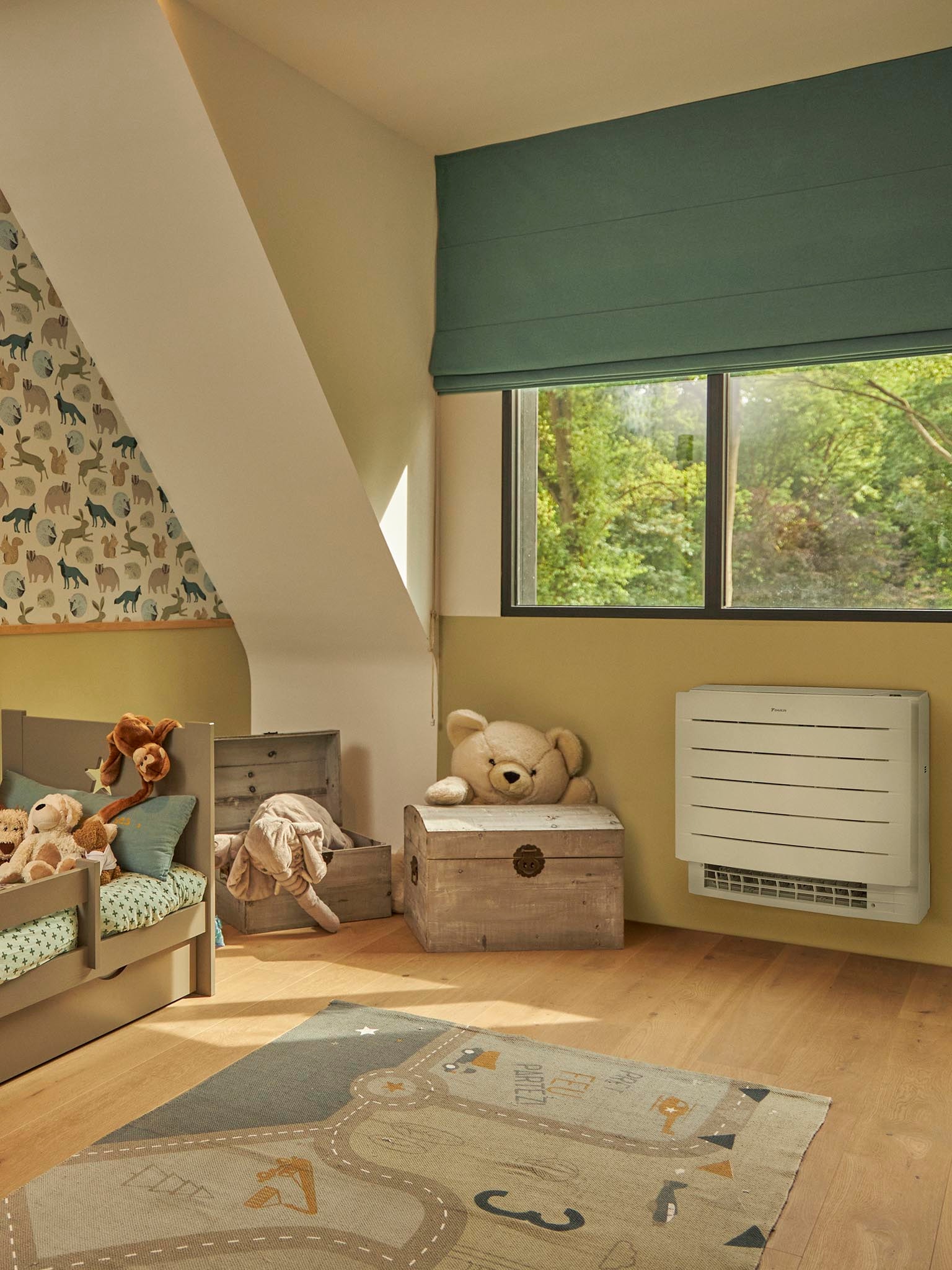 A child's nursery with soft toys and a play mat with a heat pump on the wall under the large window