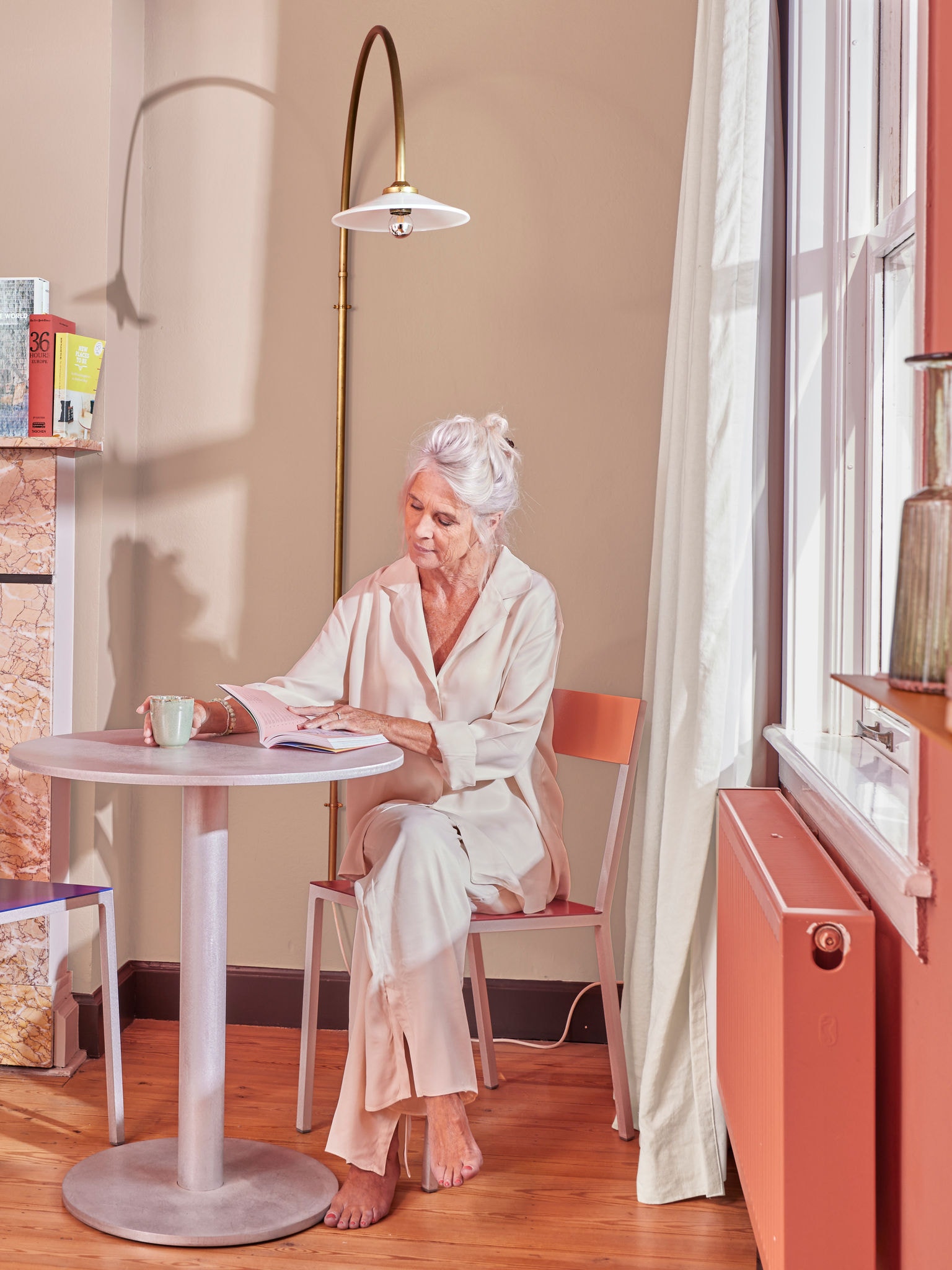 Woman reading at table by radiator using heat pump home heating system