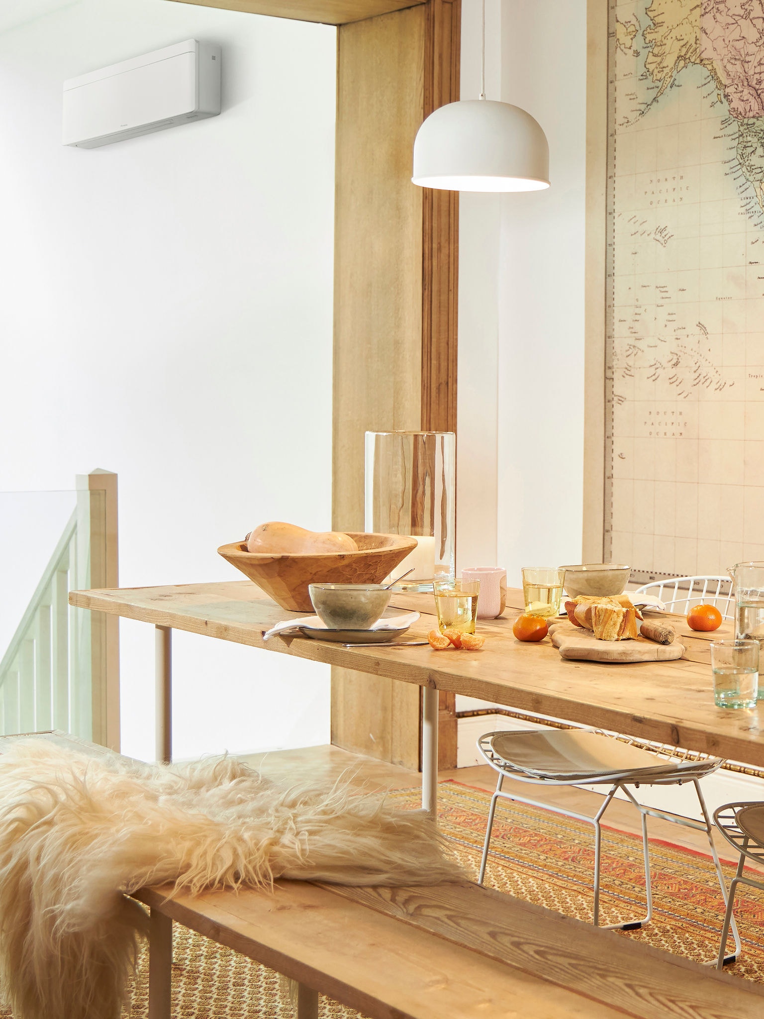 Lunch table set with food and fruit in a bright room, air conditioner visible near the staircase.