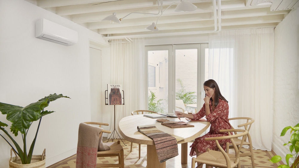 Woman sitting at table with ac unit overhead