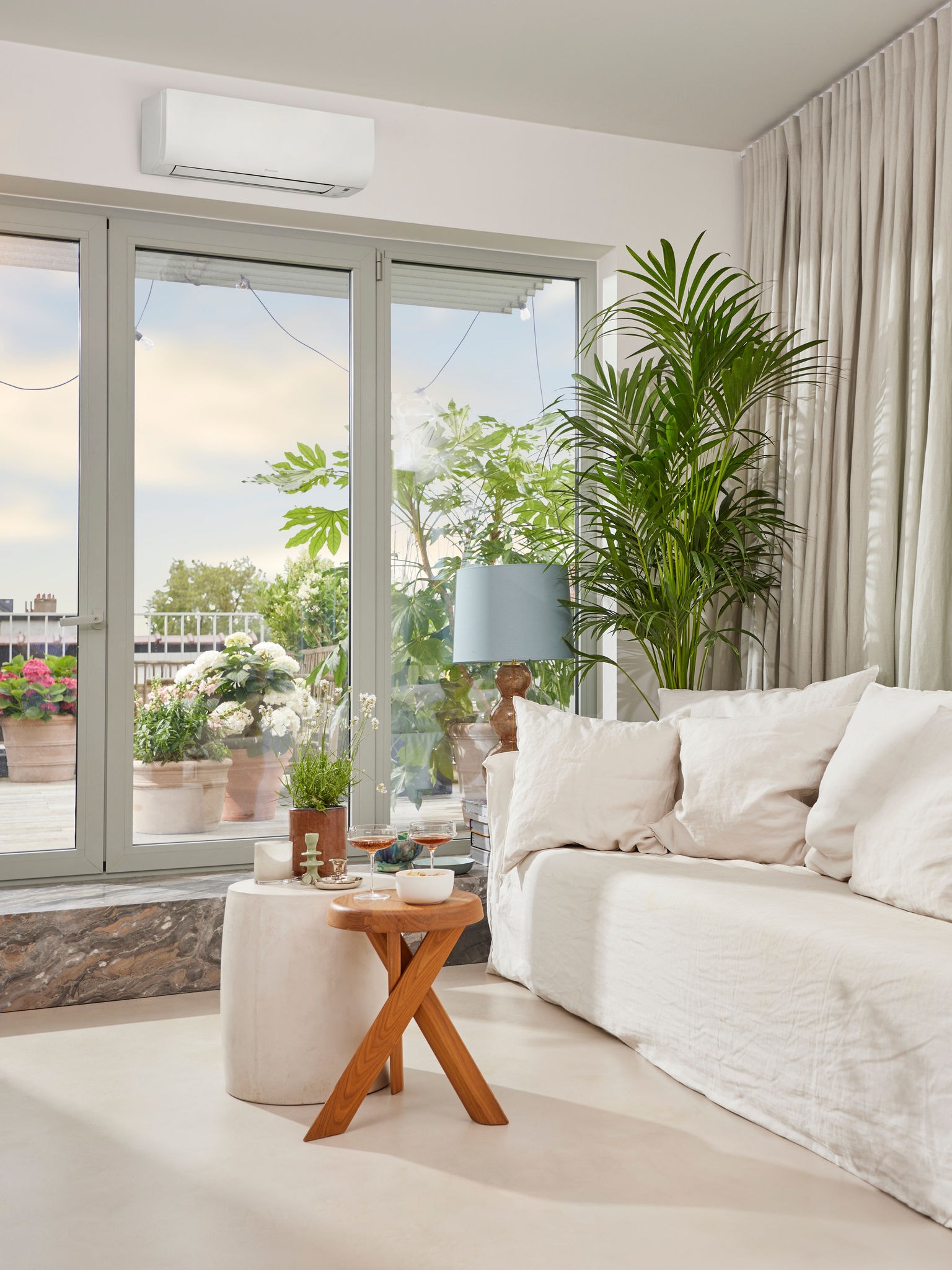 Bright, cozy living room with aperitif setup, large glass doors to terrace with an air conditioner above.