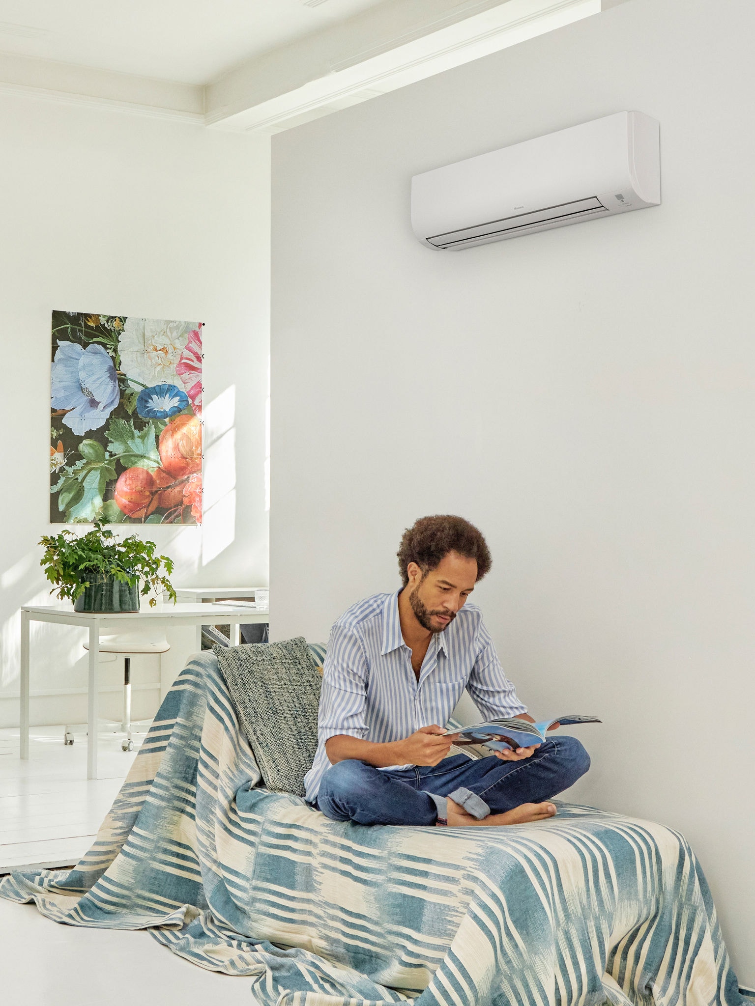 Man reading in a bright, modern living space with a heat pump mounted on the wall, illustrating the comfort and energy efficiency of heat pump technology supported by government incentive schemes