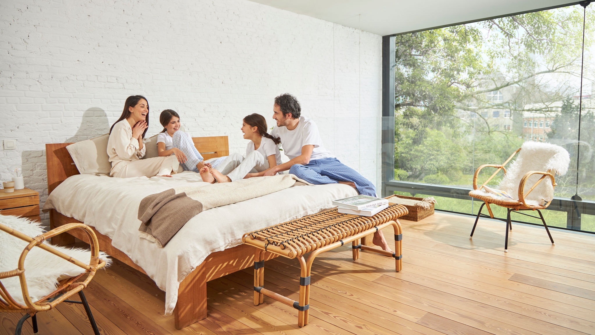 Family having a conversation on a bed in a bedroom with large glass wall, indoor air quality and abundant natural light