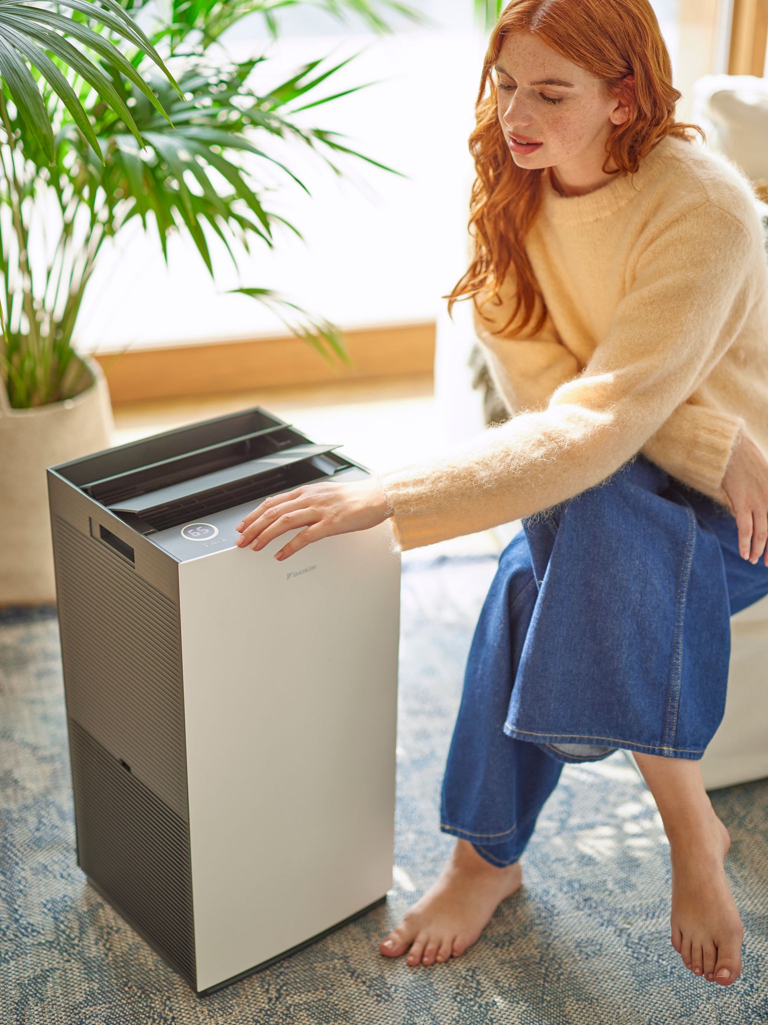 Woman in living area adjusting the controls of a Daikin air purifier