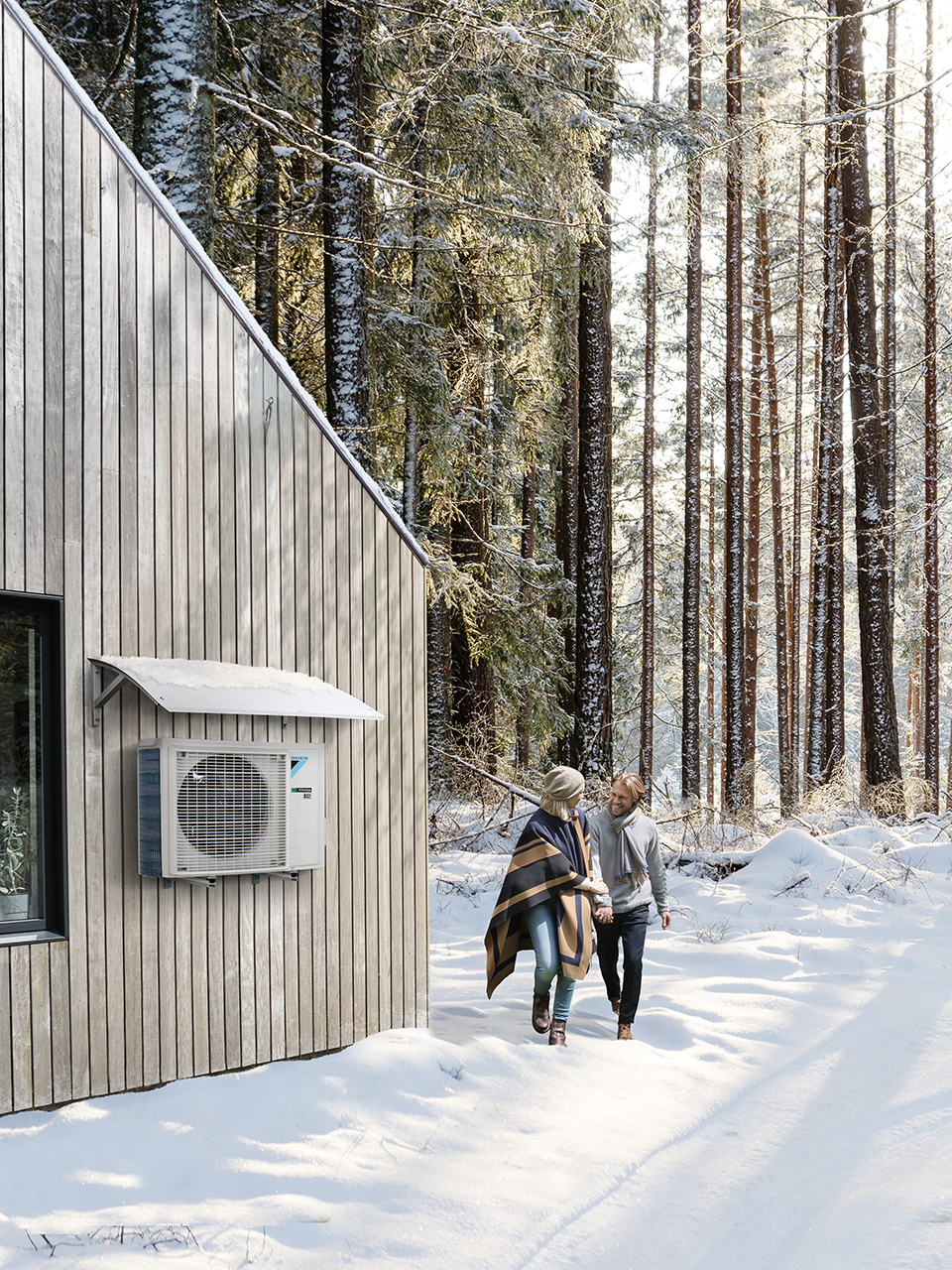 Man and woman walking in the snow with Daikin outdoor unit