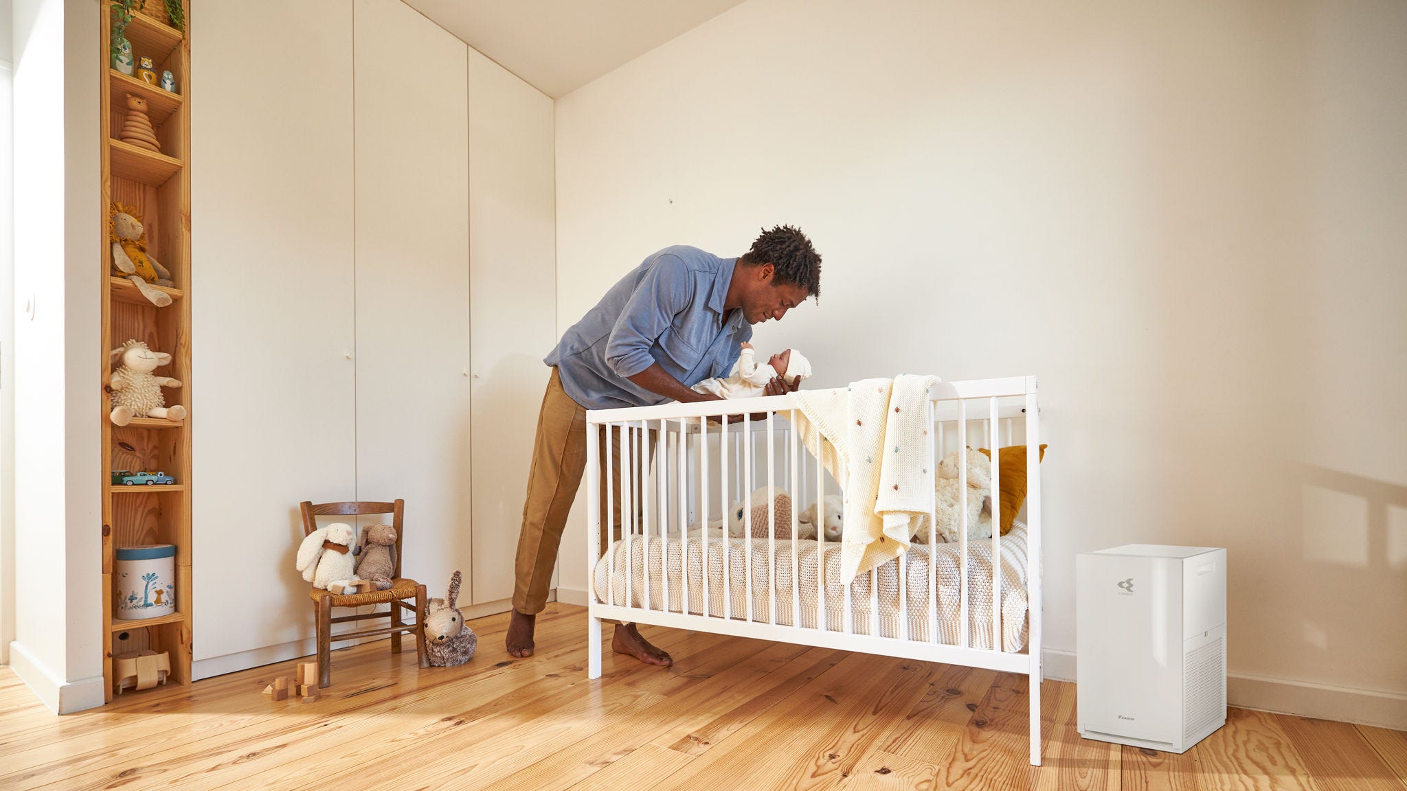 Dad putting baby to bed in clean indoor air with a Daikin air purifier, in a well-ventilated nursery