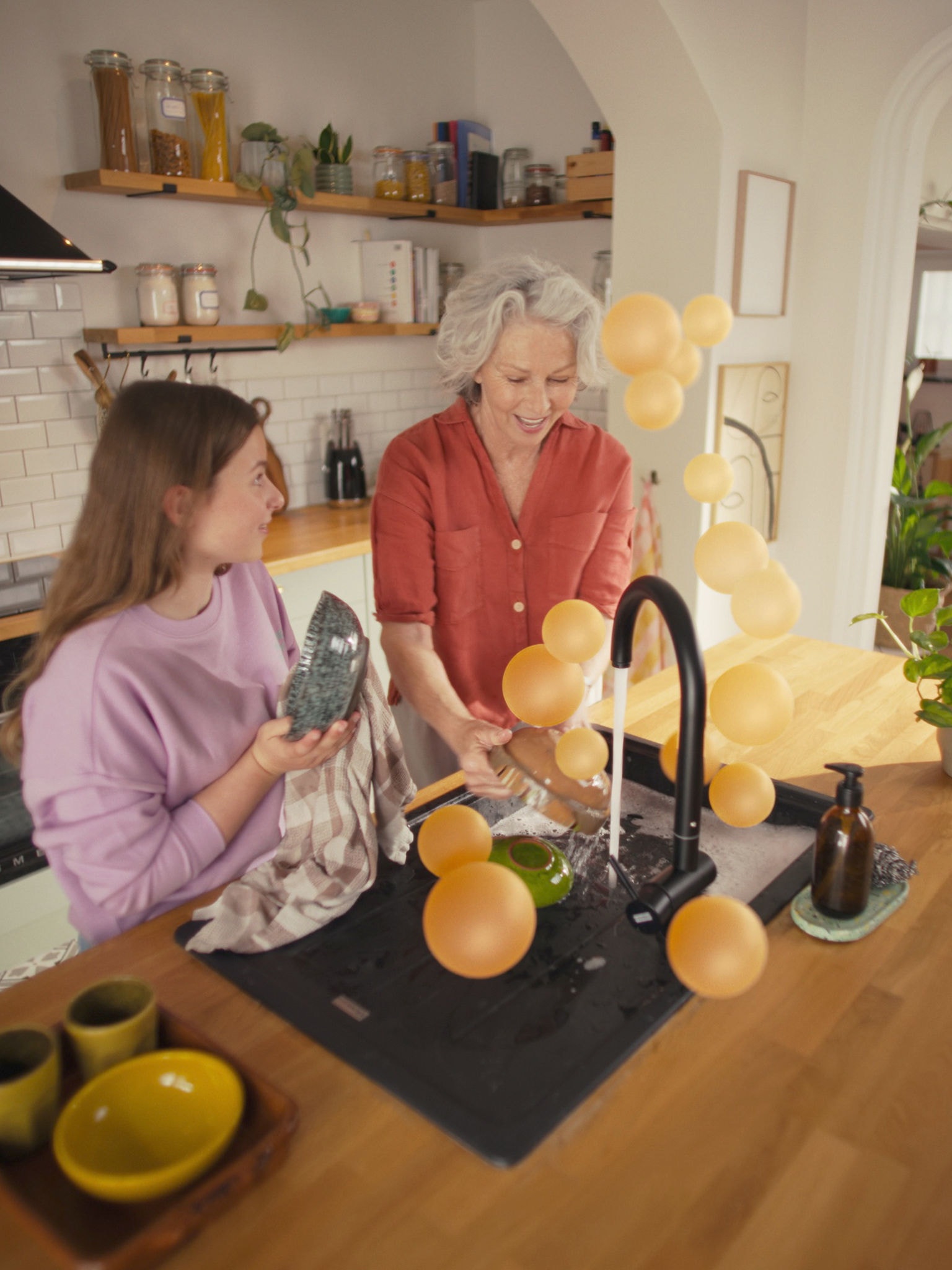 Woman and girl washing up at kitchen sink